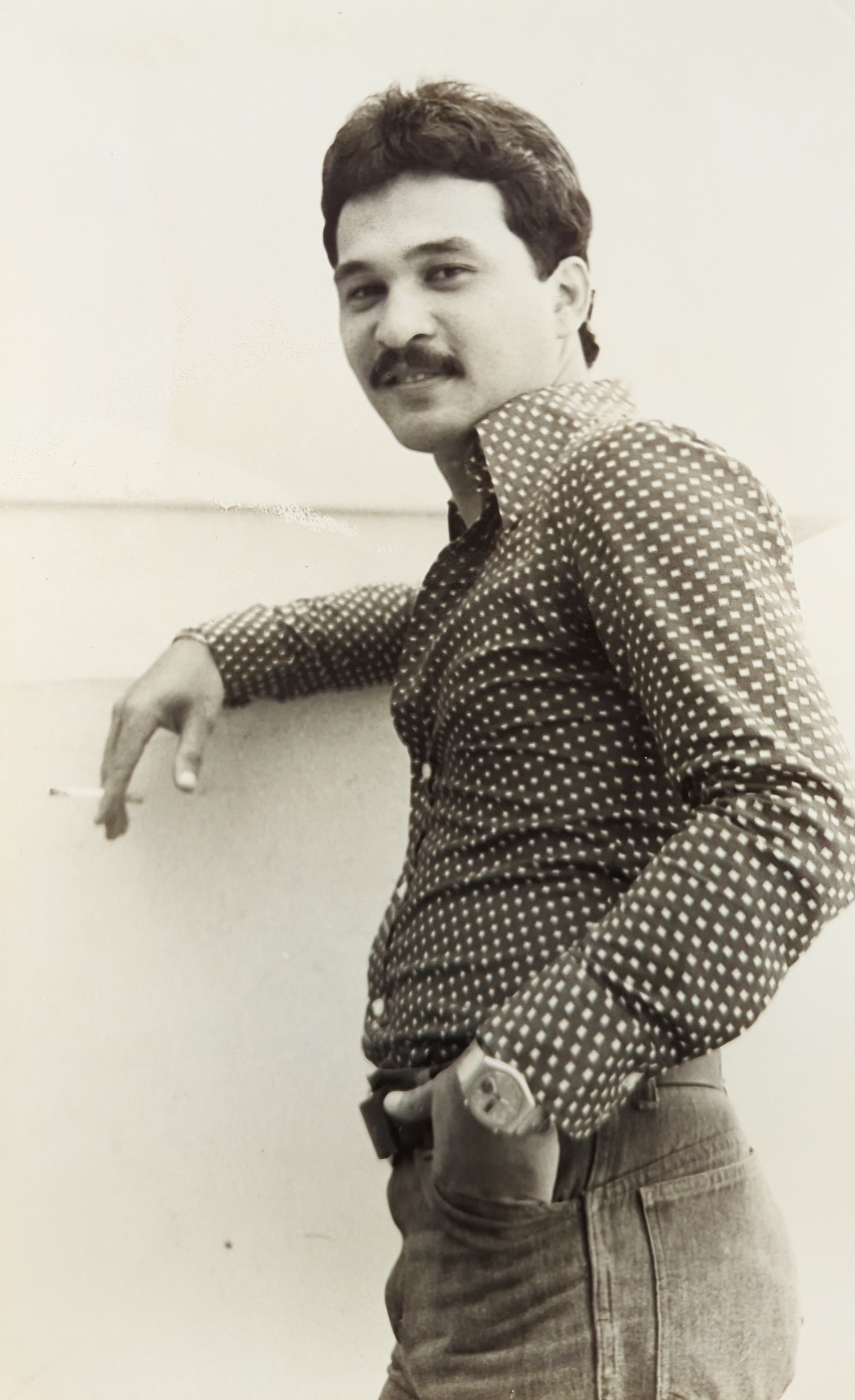 Black and white photo of Papa posing with a cigarette in front of a wall for his entry in the Asian Institute of Management yearbook c. 1978